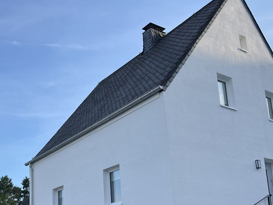 Außenansicht: weißes Einfamilienhaus mit neuem Schieferdach